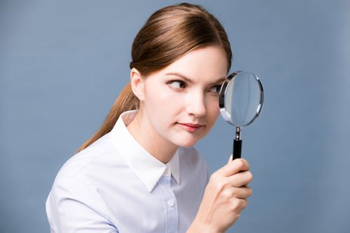 虫眼鏡を見つめる女性