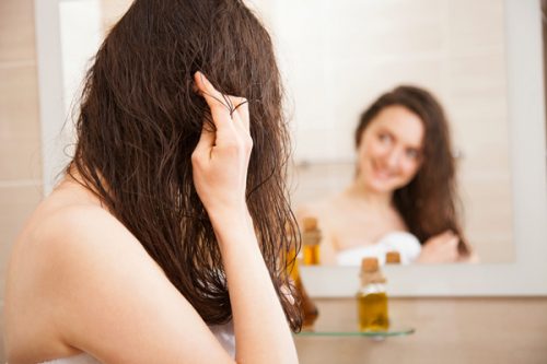 鏡の前で髪をケアする女性