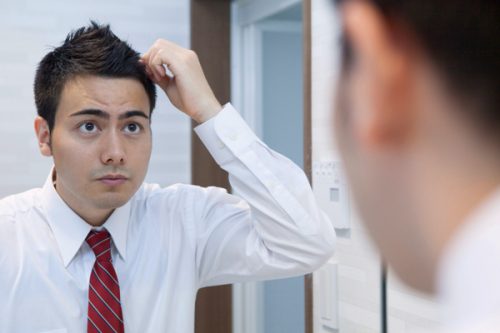 鏡の前で髪をセットする男性